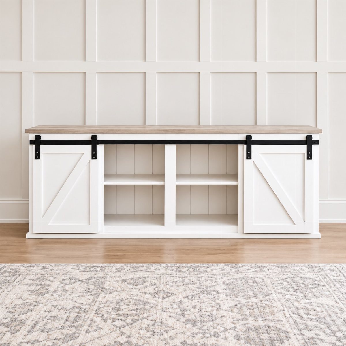 White storage console with sliding barn doors and open shelves against paneled wall.