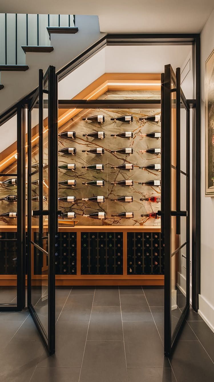 Wine cellar with glass doors and bottle racks built under a staircase.