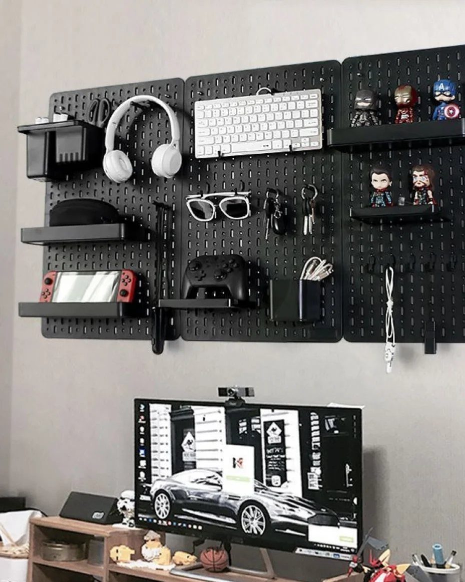 Black pegboard with shelves holding gaming accessories and figurines on a grey wall.