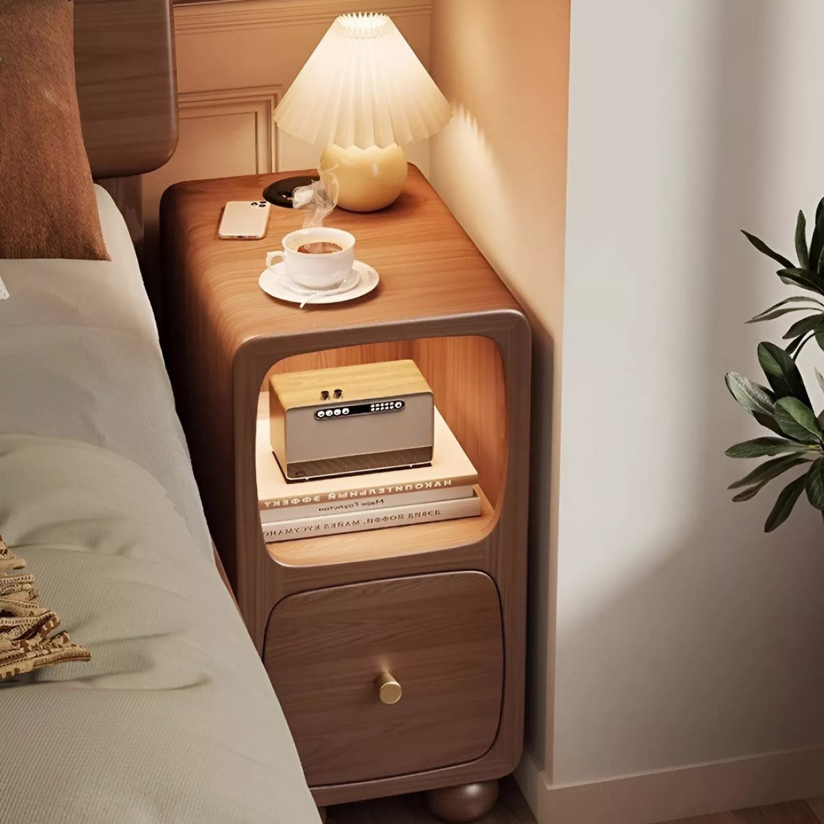 Rounded brown wooden bedside table with a lamp, radio, and coffee cup.