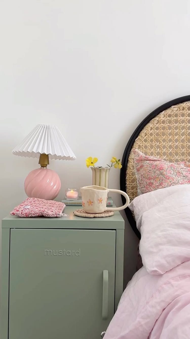 Sage green metal locker bedside table with a pink lamp and floral accents.