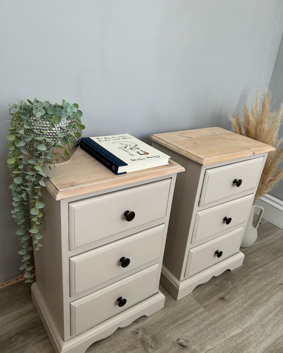Two light grey wooden nightstands with natural wood tops and black drawer knobs.