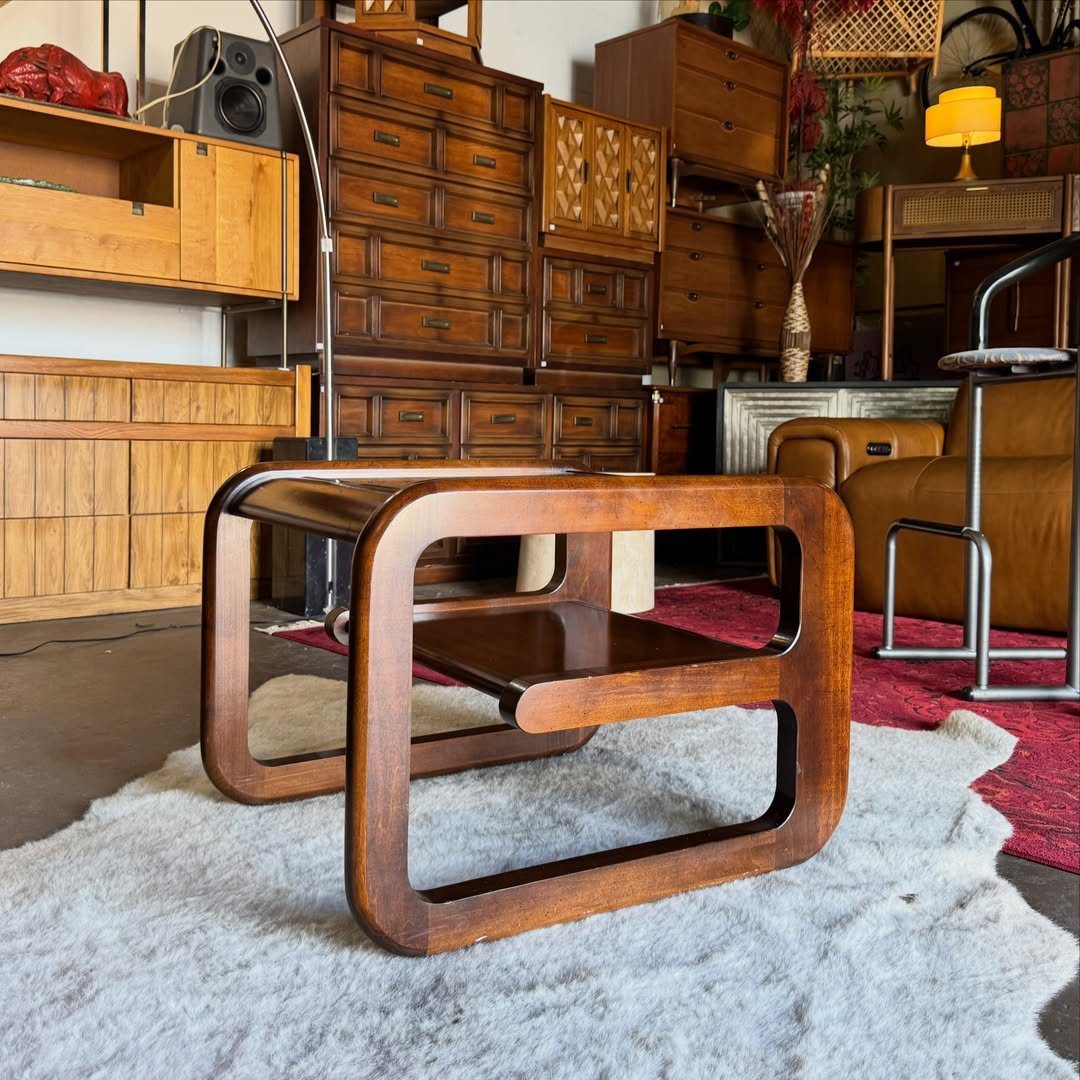 Curved dark wood end table with a lower shelf on a white rug