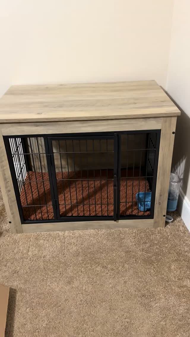 Wooden end table with a built-in black metal dog crate and brown pet bed.