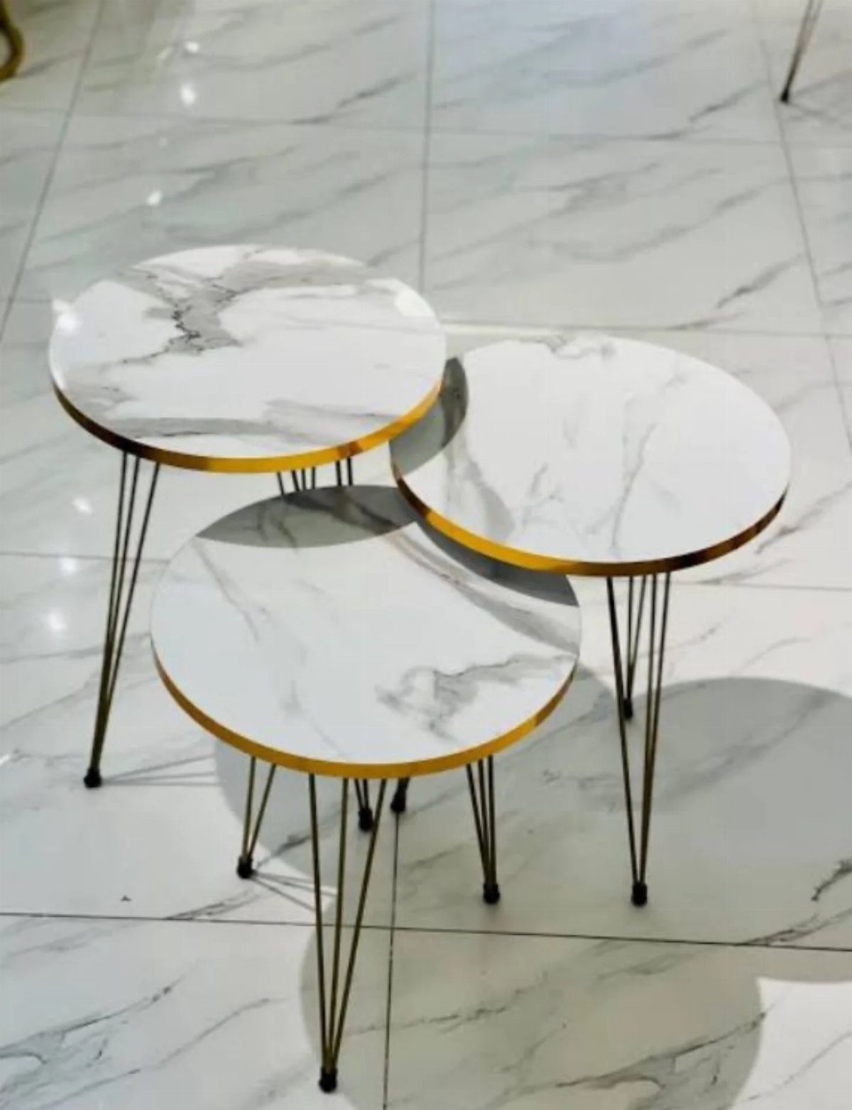 Three round marble-top nesting tables with gold edges and black hairpin legs.