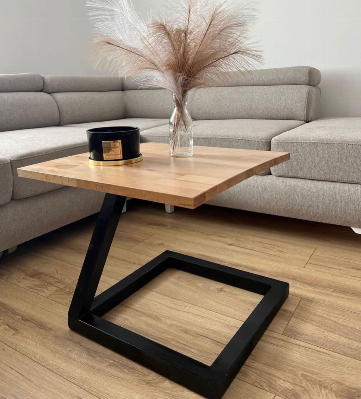 Square end table with light wood top and black metal geometric base