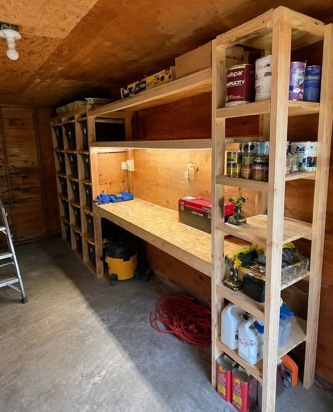 DIY Garage Organization: 17 Ideas to Build and Install 4 Wooden garage workbench with open shelving and a row of black storage bins.