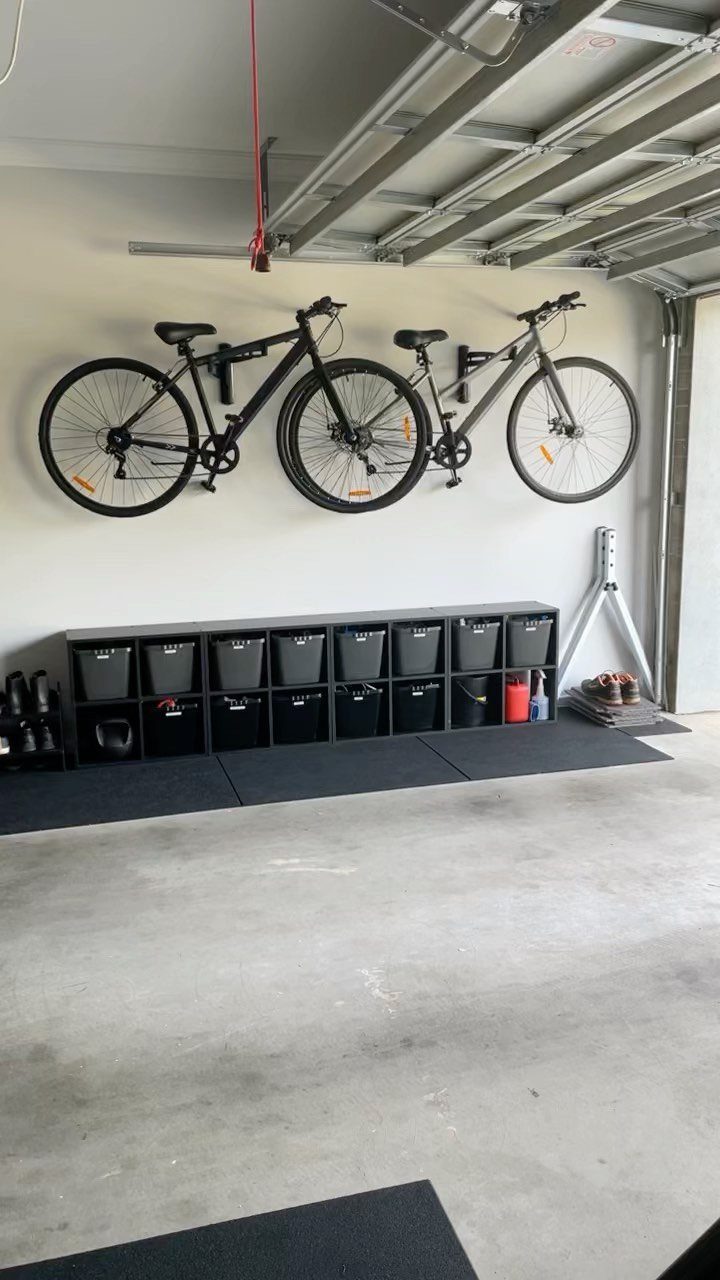 DIY Garage Organization: 17 Ideas to Build and Install 1 Bicycles mounted on a white wall above black storage bins in a garage.