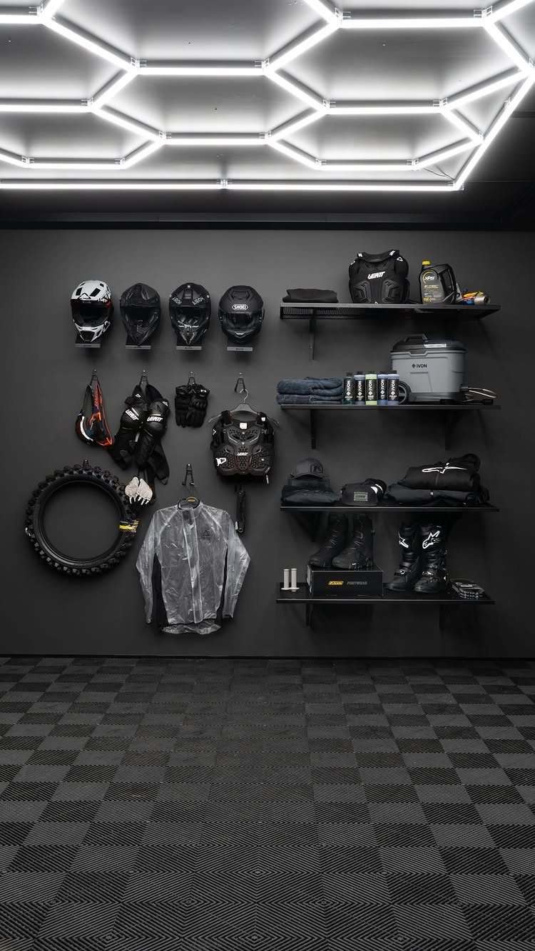 DIY Garage Organization: 17 Ideas to Build and Install 17 Motorcycle gear organized on black walls with hexagonal ceiling lights and checkered flooring.