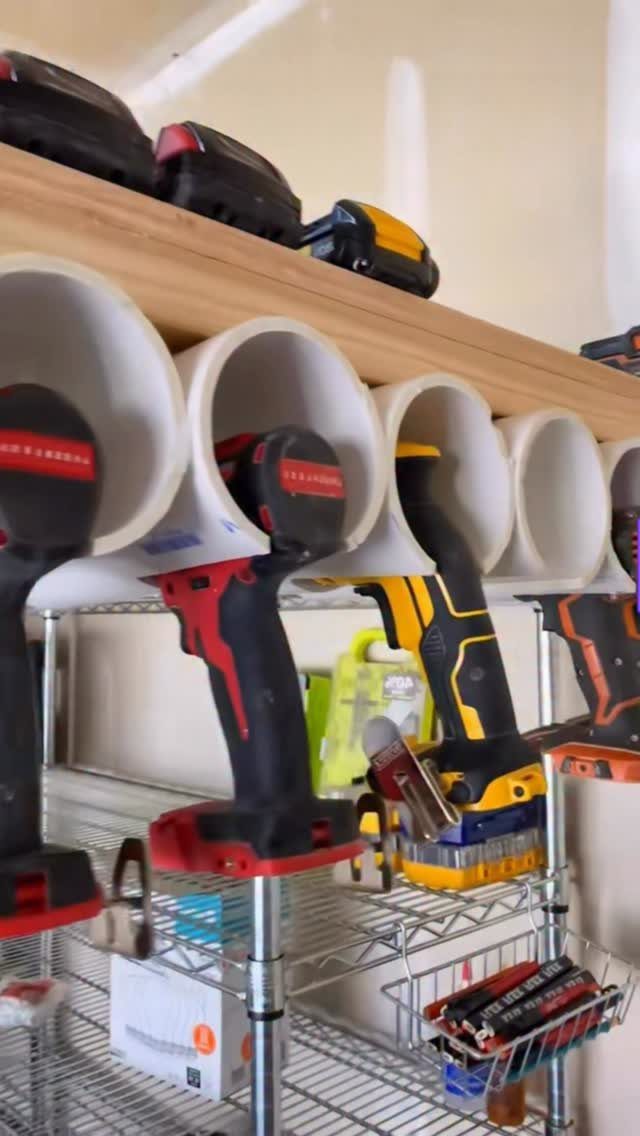DIY Garage Organization: 17 Ideas to Build and Install 8 Power drills stored in white PVC pipe holders under a wooden shelf.