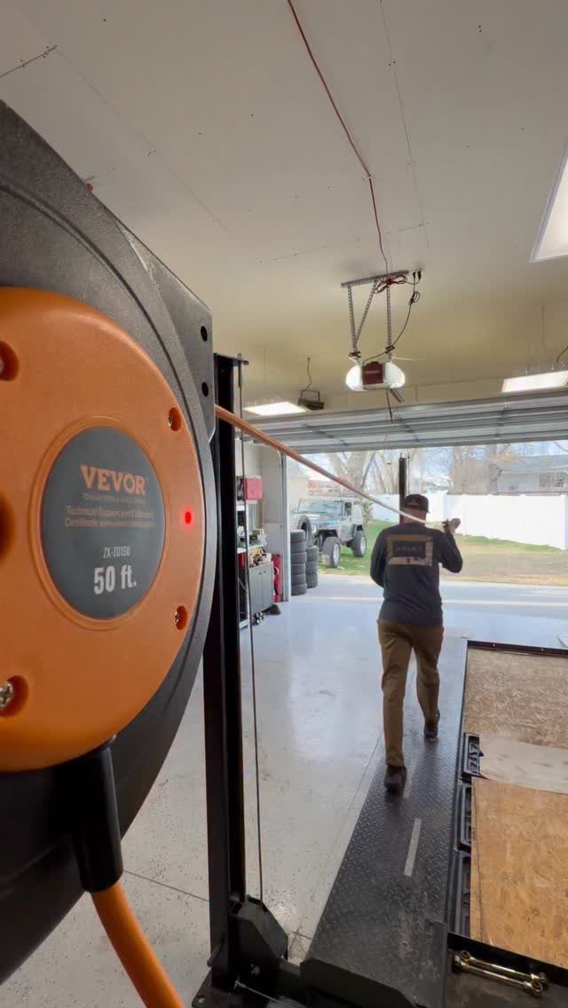 DIY Garage Organization: 17 Ideas to Build and Install 5 Retractable cord reel mounted in a garage with a man pulling the orange cable.