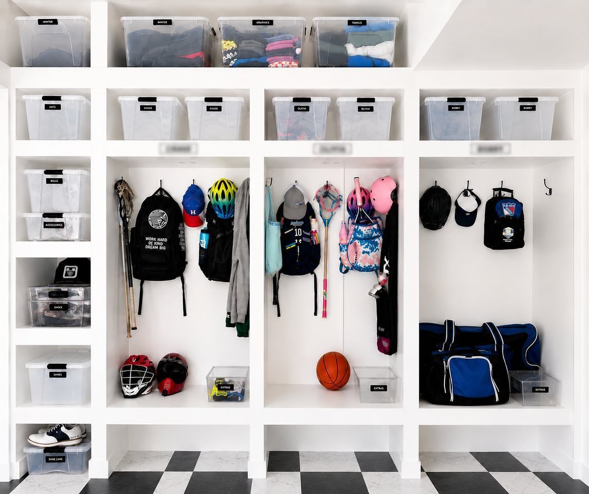 DIY Garage Organization: 17 Ideas to Build and Install 14 White built-in storage cubbies with sports gear and clear bins on checkered flooring.