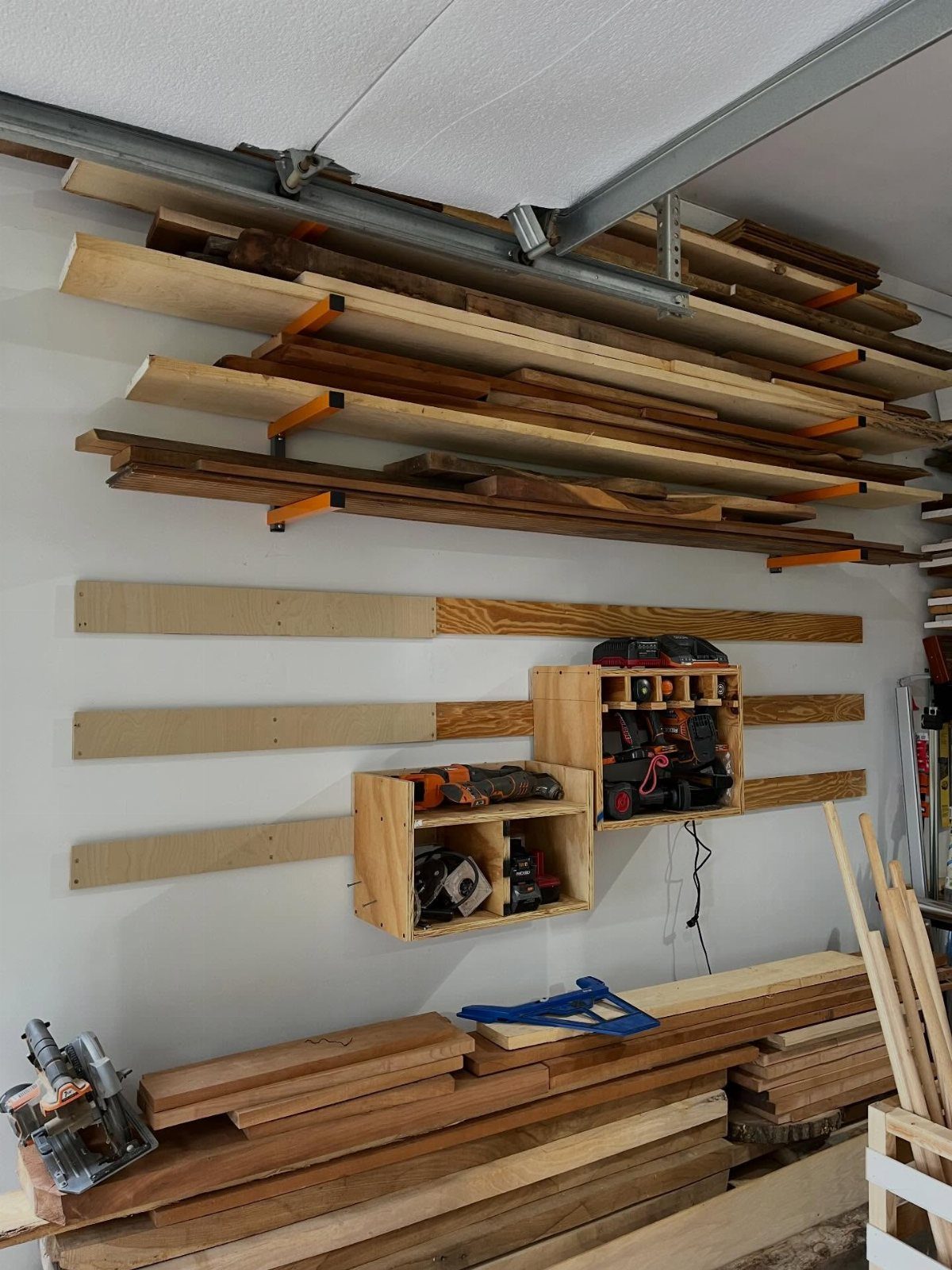 DIY Garage Organization: 17 Ideas to Build and Install 16 Wooden lumber racks and tool organizers mounted on a white garage wall.