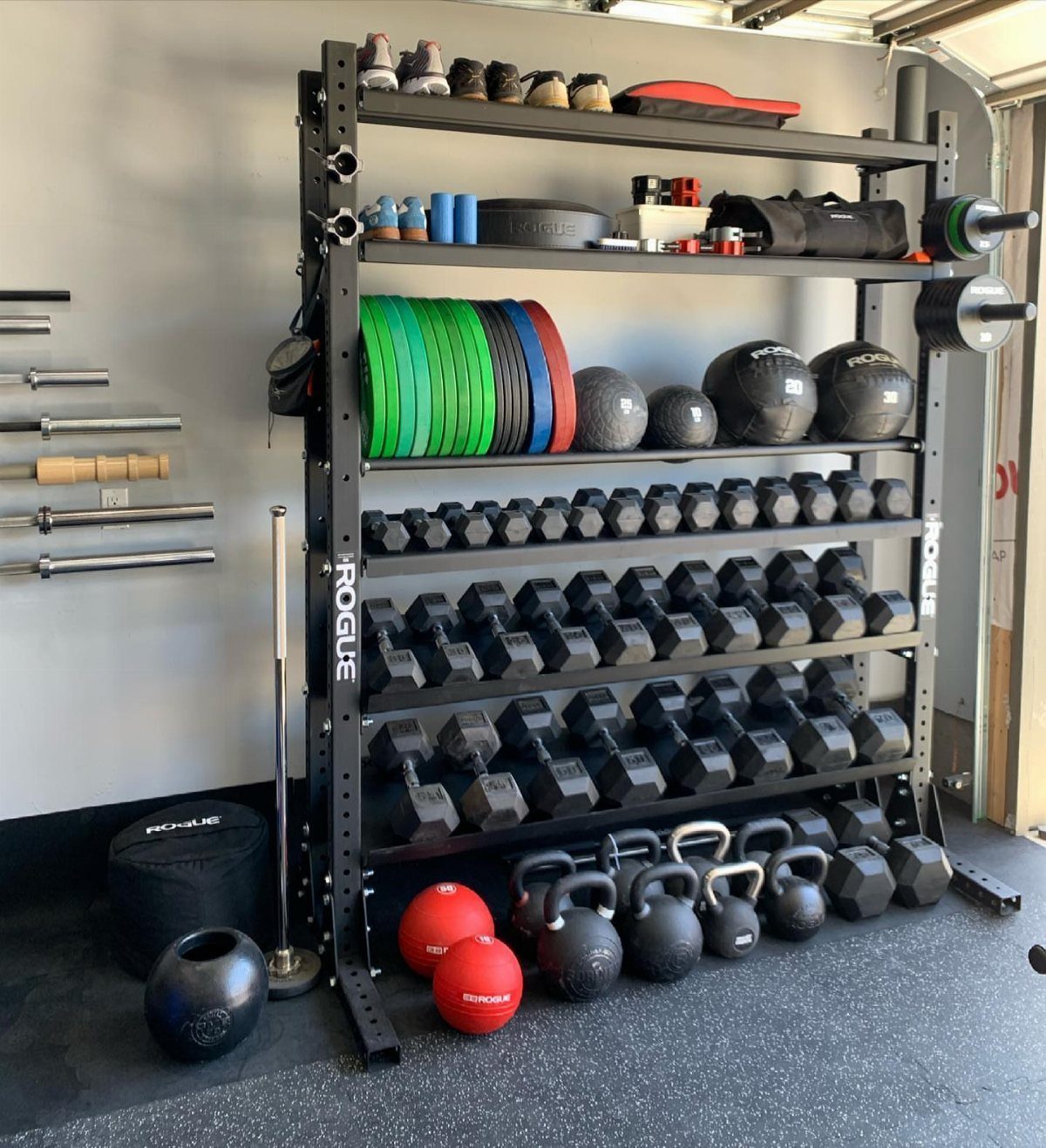 17 Garage Storage Inspiration Ideas to Organize Any Space 13 Black metal weight rack holding dumbbells, kettlebells, and medicine balls in a garage gym.