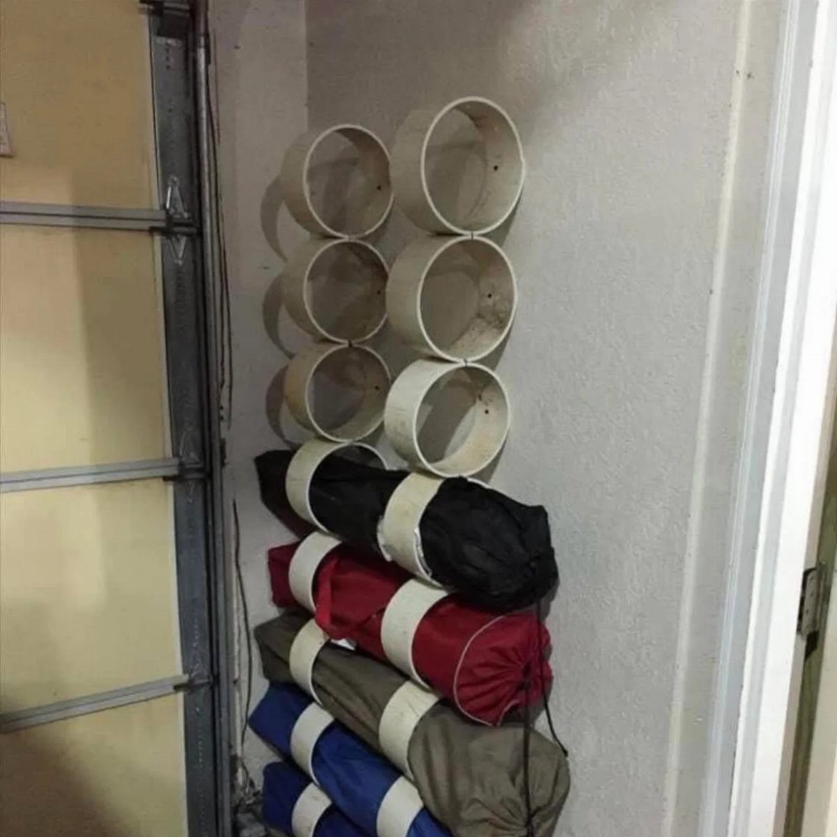 17 Garage Storage Inspiration Ideas to Organize Any Space 11 PVC pipe wall mounts holding folded camping chairs in a garage setting.