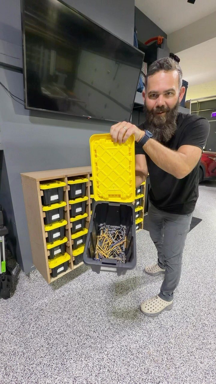 17 Garage Storage Inspiration Ideas to Organize Any Space 9 Man holding a grey and yellow storage bin filled with screws in a garage.