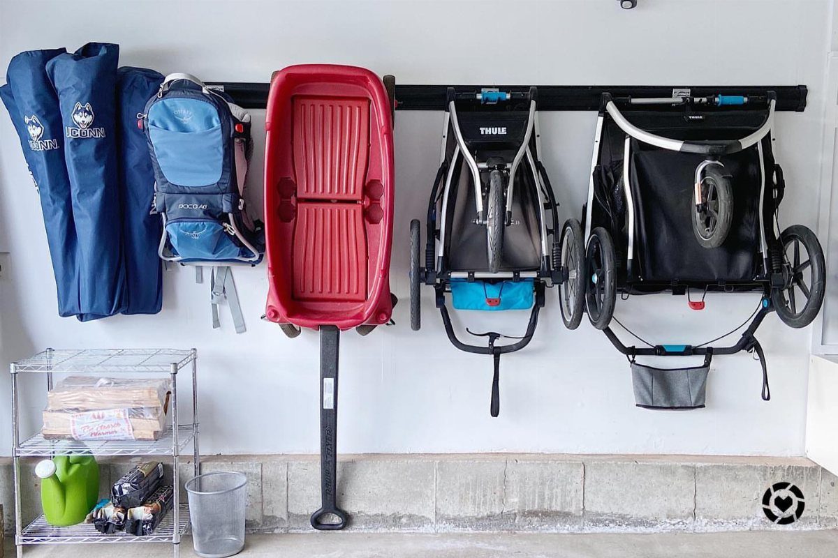 17 Garage Storage Inspiration Ideas to Organize Any Space 8 Red wagon and strollers hanging from a black wall rail in a garage.