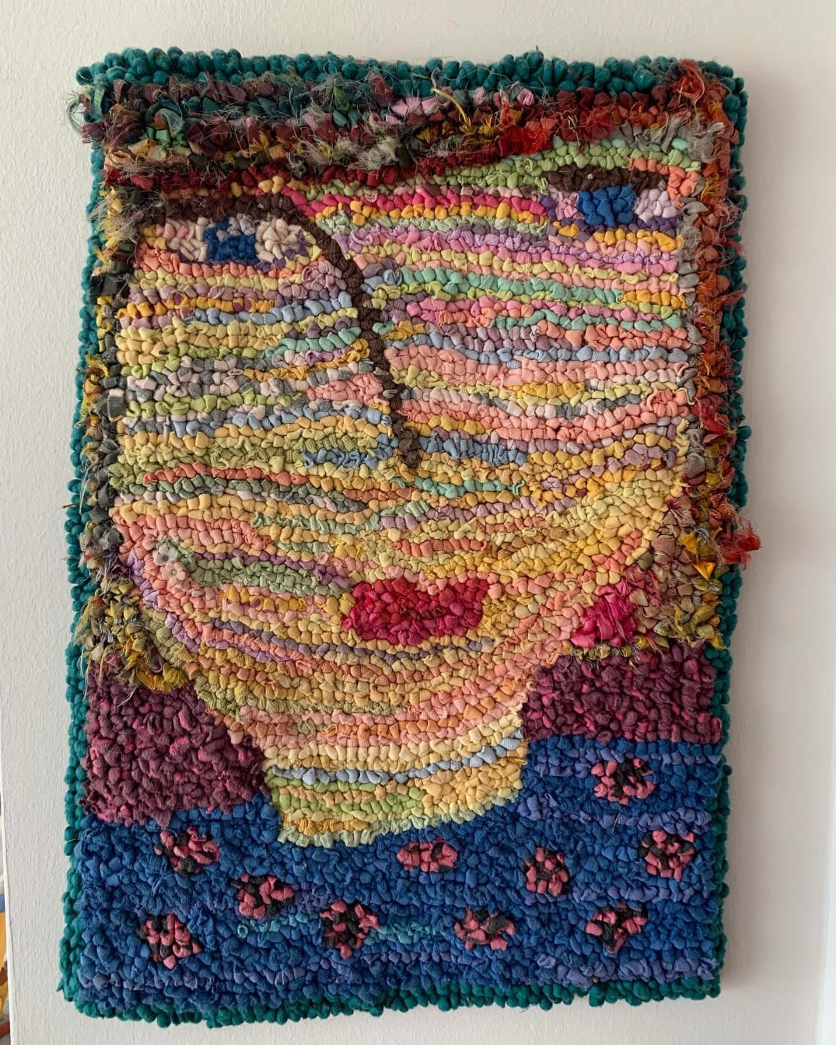 8 Ways to Make a Rag Rug From Braided to Woven 5 Woven rag rug wall hanging depicting a colorful stylized face on a white wall
