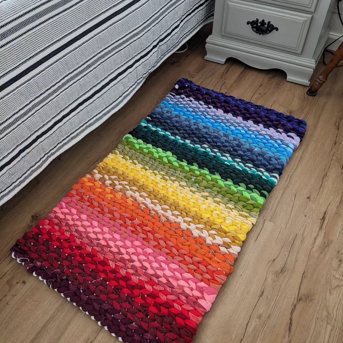 8 Ways to Make a Rag Rug From Braided to Woven 7 Rainbow colored rag rug lying on a light brown wooden floor.