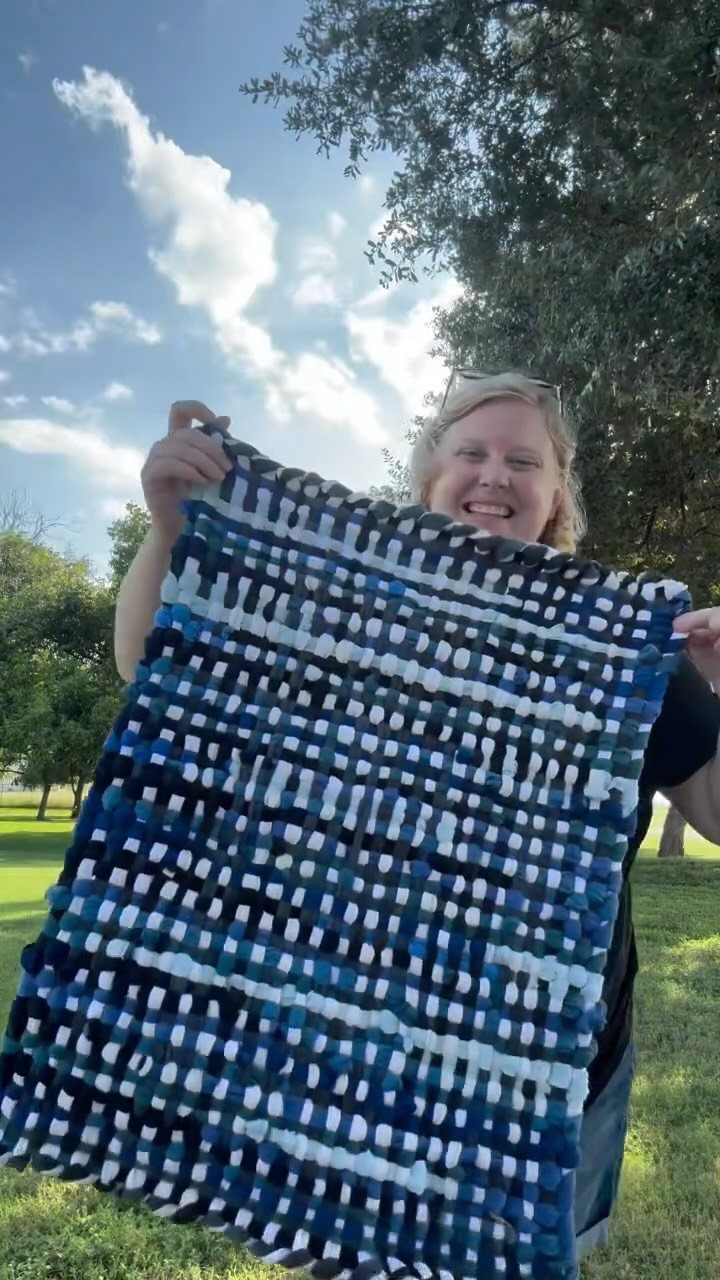 8 Ways to Make a Rag Rug From Braided to Woven 3 Woman holding a blue and white woven rag rug outdoors in a park