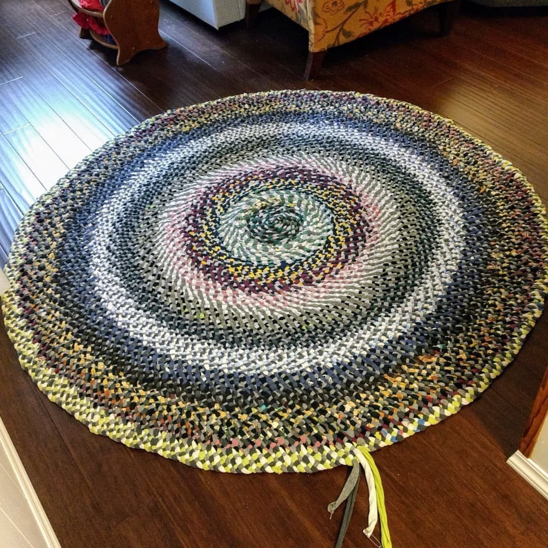Circular braided rag rug with multicolored fabric strips on a dark wood floor.