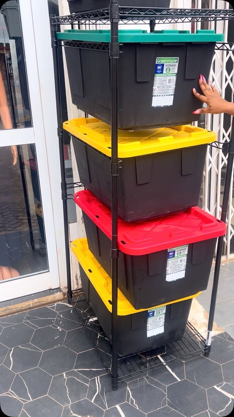 Black metal storage rack holding plastic totes with colorful lids on tiled floor